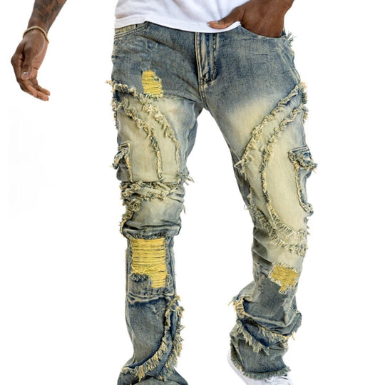 Men's patchwork fringe slightly flared stretch jeans in blue denim with distressed details and trendy rips.