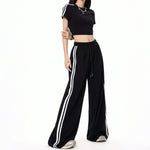 Black wide-leg casual pants with white stripes and matching cropped top for a sporty look.