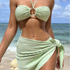 Women in a stylish green striped bikini with a wrap skirt on the beach, ideal for summer vacations.