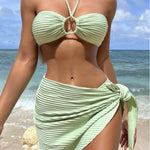 Women in a stylish green striped bikini with a wrap skirt on the beach, ideal for summer vacations.