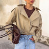 Women's khaki double breasted blazer coat with drop-shoulder sleeves, styled with a brown bag and blue jeans.