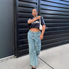 Fashionable woman wearing denim wide leg trousers and a cropped black t-shirt, styled with a modern look.