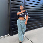 Fashionable woman wearing denim wide leg trousers and a cropped black t-shirt, styled with a modern look.