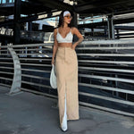 Woman in a white top and khaki skirt posing in an urban setting, showcasing summer fashion trends.