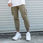 Men's khaki running workout pants with cargo pockets, paired with white sneakers, ideal for fitness and leisure activities.