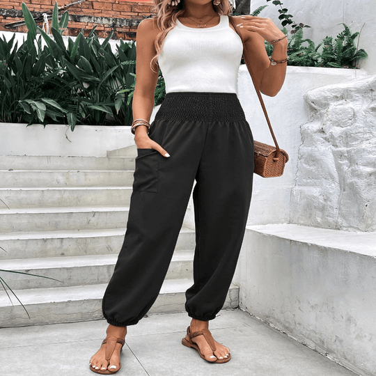 Elasticated high-waisted wide-legged niners in black, featuring long sleeves and pockets, worn casually outdoors.