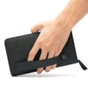 Hand holding a black first layer cowhide clutch wallet with a zipper and strap, showcasing urban simplicity style.