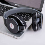 Sports headphones resting on a laptop, featuring a sleek black design and cushioned ear pads for comfort.
