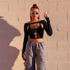 Model wearing an off-shoulder long-sleeve backless halter neck crop top in black with gray cargo pants.