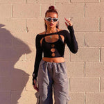 Model wearing an off-shoulder long-sleeve backless halter neck crop top in black with gray cargo pants.