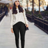 Stylish woman in black one-piece yoga leggings walking outdoors in a cozy sweater and hat.