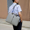 Portable laptop bag in gray, designed for cross-body wear, showcasing waterproof Oxford cloth material.