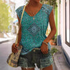 Woman wearing geometric printed sleeveless top in vibrant teal, paired with denim shorts and a stylish bag, summer fashion.