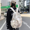 Large capacity backpack for students in cream color, featuring a plush keychain and urban style. Ideal for leisure travel.