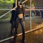 Woman wearing slim black PU leather casual pants with high waist and wide leg straps against a reflective window.