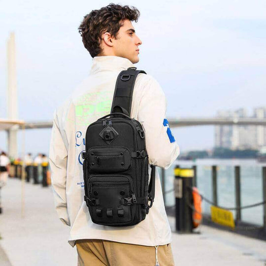 Man wearing a tactical chest outdoor messenger bag in black, ideal for sports and daily use.