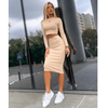 Fashionable women's solid color two-piece top and hip skirt set, featuring a minimalist look with sporty sneakers.