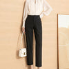 Women's high waist straight leg black pants paired with a light blouse and a stylish handbag.