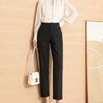 Women's high waist straight leg black pants paired with a light blouse and a stylish handbag.