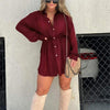 Stylish women's long sleeve burgundy jumpsuit dress with button front and waist tie, paired with over-the-knee boots.