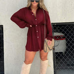 Stylish women's long sleeve burgundy jumpsuit dress with button front and waist tie, paired with over-the-knee boots.
