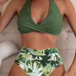Women's multicolor high-waisted swimsuit with green halter top and tropical leaf print briefs.