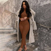 Woman in brown solid color yoga jumpsuit with a stylish coat on marble staircase.