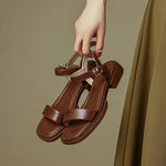 Brown leather flat sandals with ankle buckle, showcasing retro French style and tassel details.
